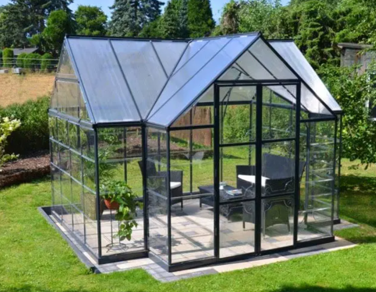 Glass greenhouse and garden room on a paver base in a landscaped backyard