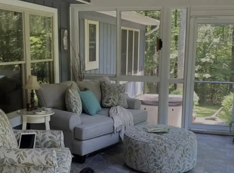 Screened-in sunroom addition with lounge seating overlooking a wooded backyard