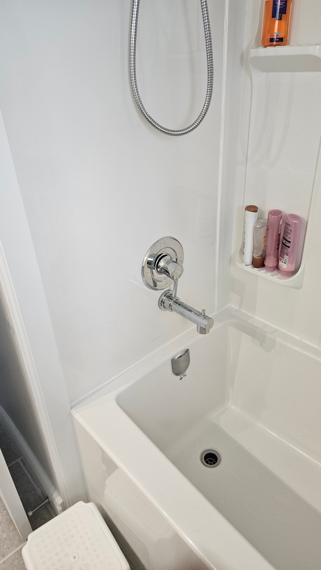 New bathtub surround, shower fixture and built-in shelving in a bathroom renovation