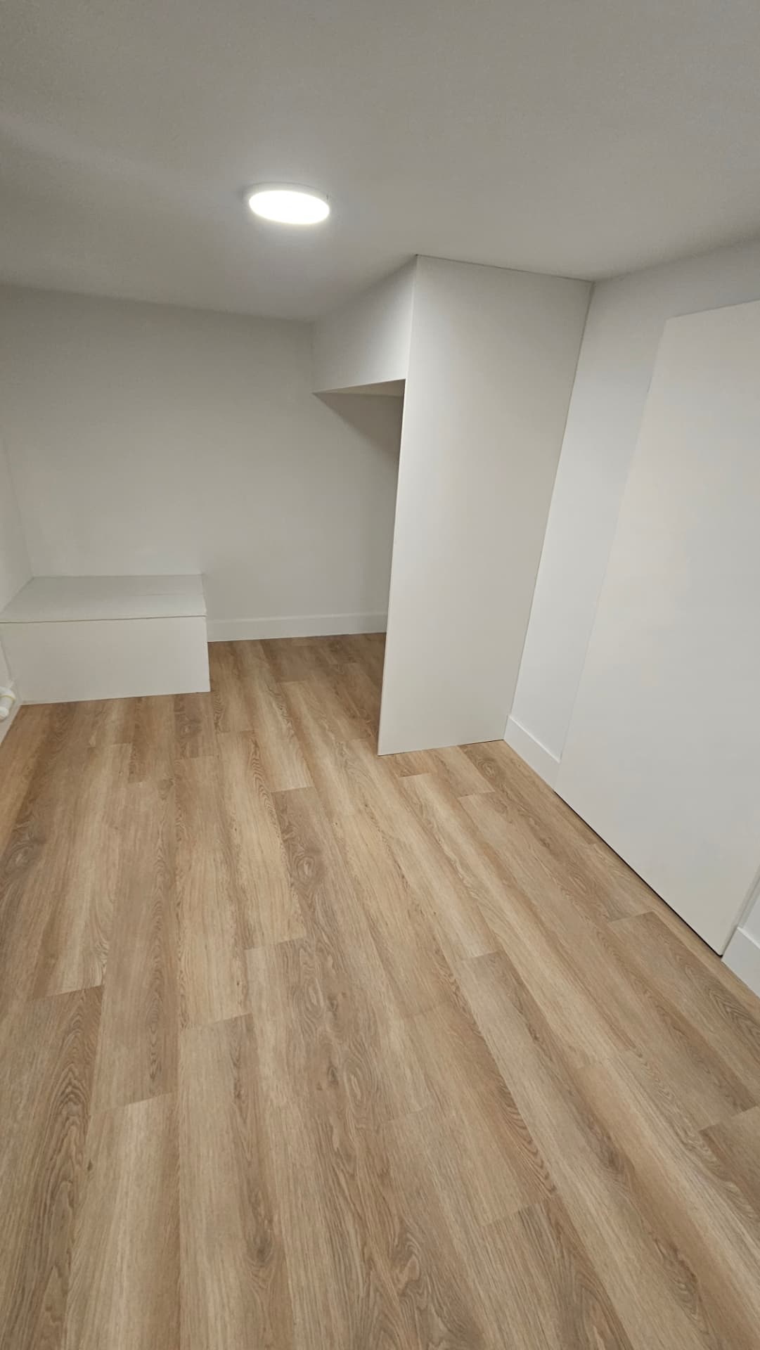 Finished lower-level room with new flooring and built-in storage