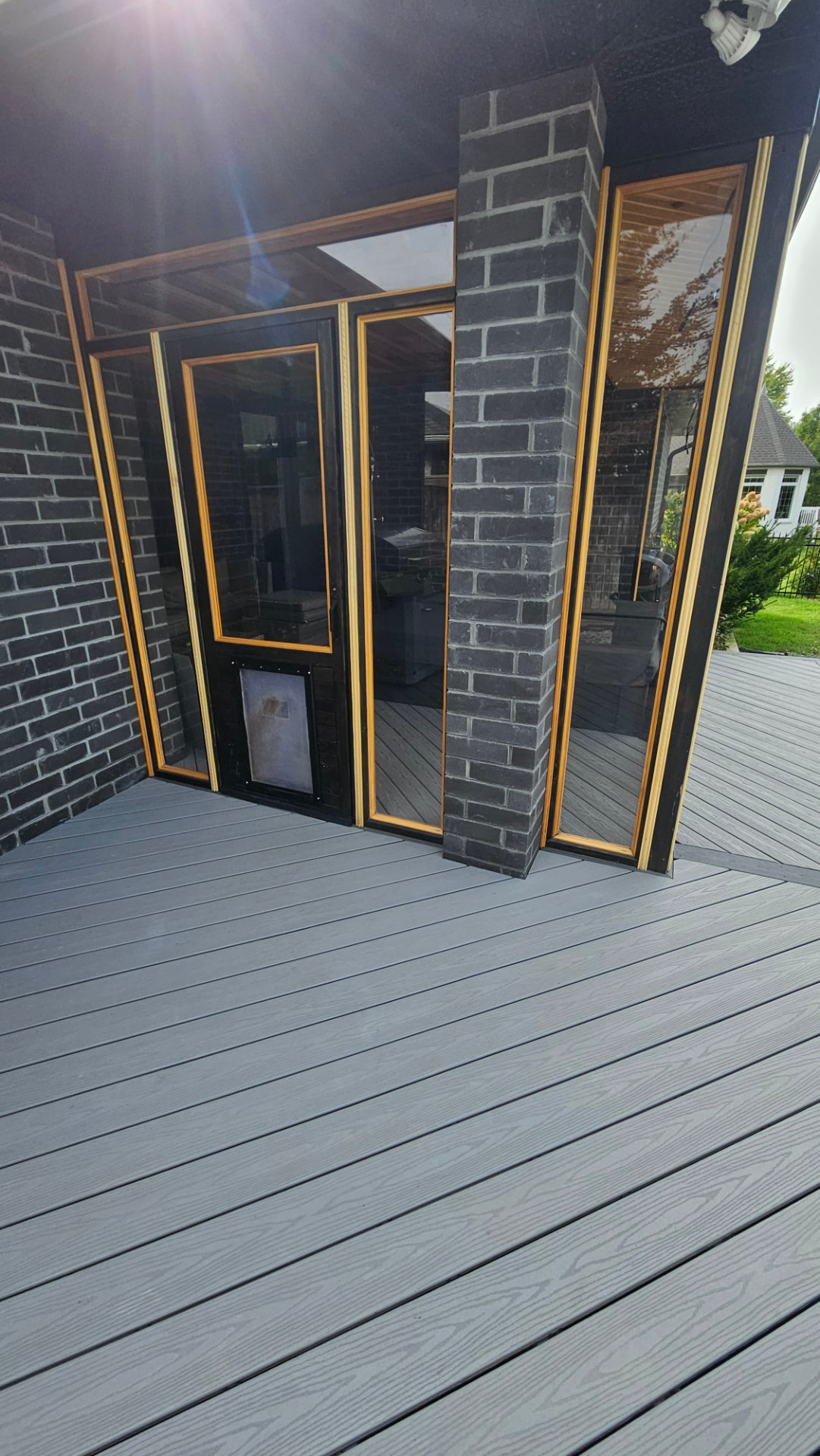 Folding glass doors with wood-trim frames opening from a brick addition onto a composite deck