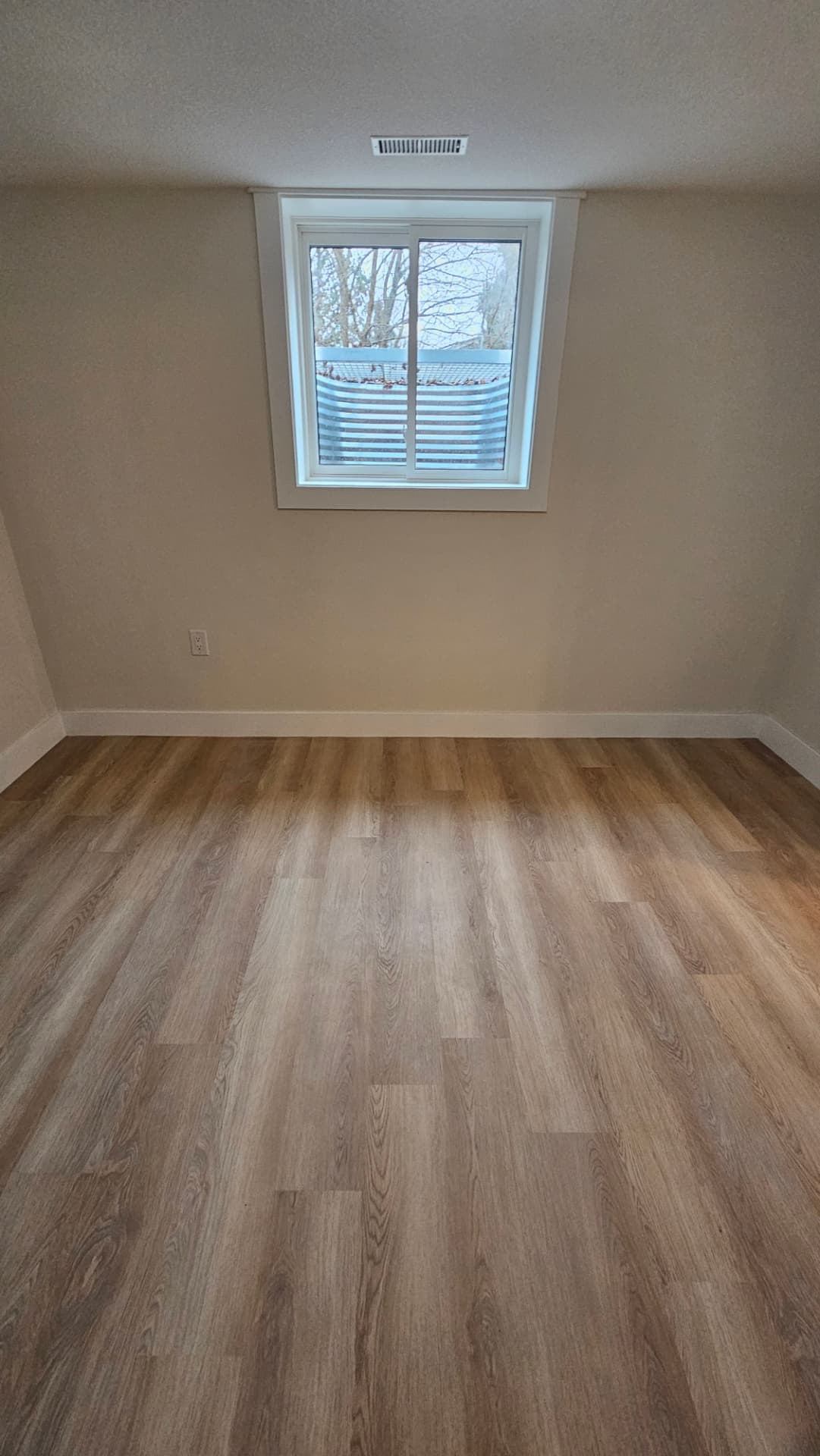 Finished lower-level room with new flooring, trim and window