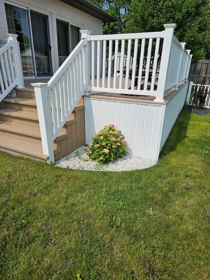 Raised backyard deck with white vinyl railing and stairs