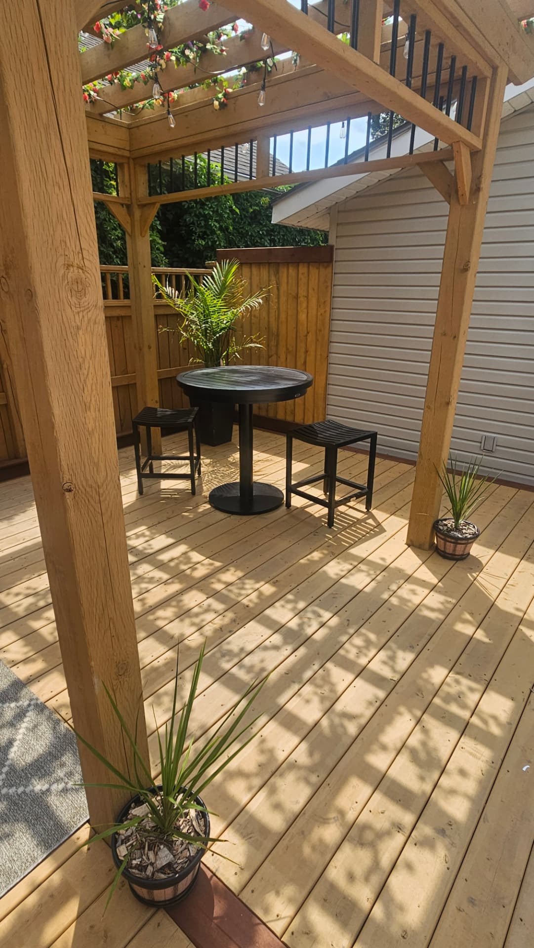 Bar table and stools under a cedar pergola on a new cedar deck