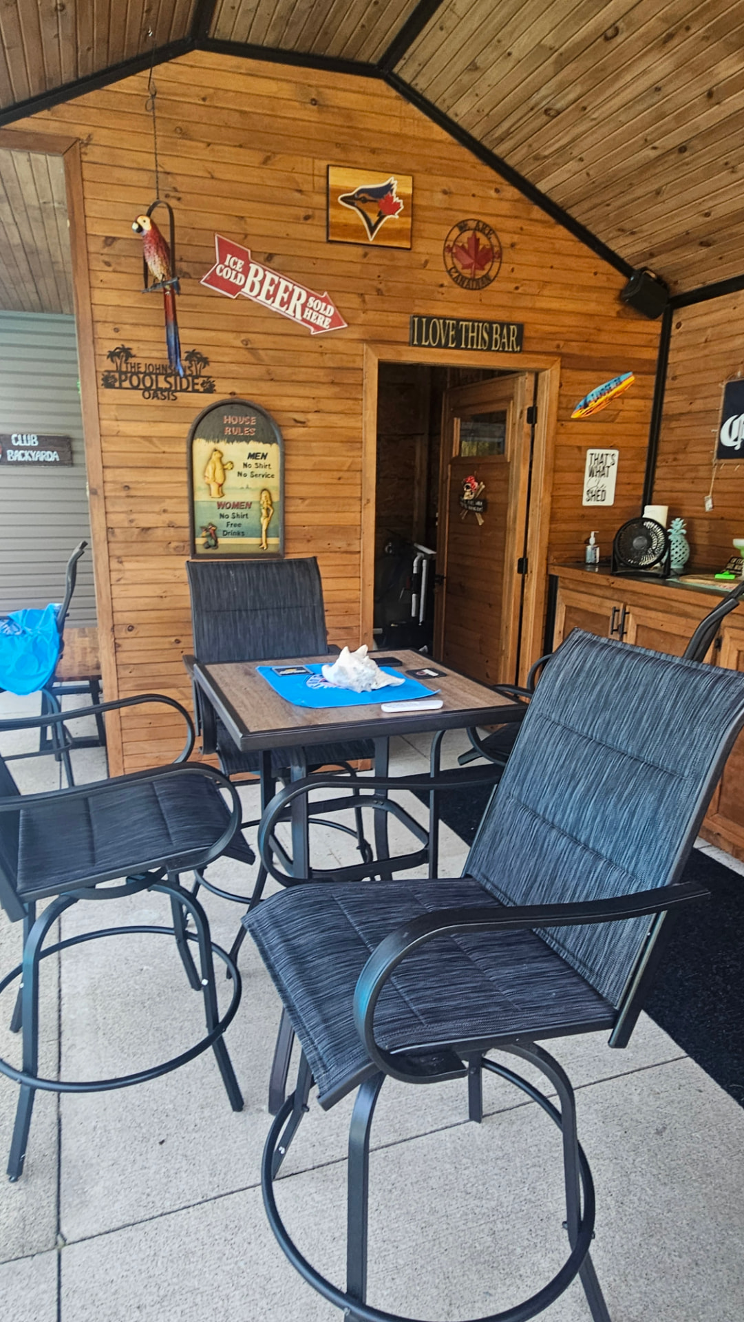 Cedar-lined cabana bar interior with vaulted ceiling, bar table and stools