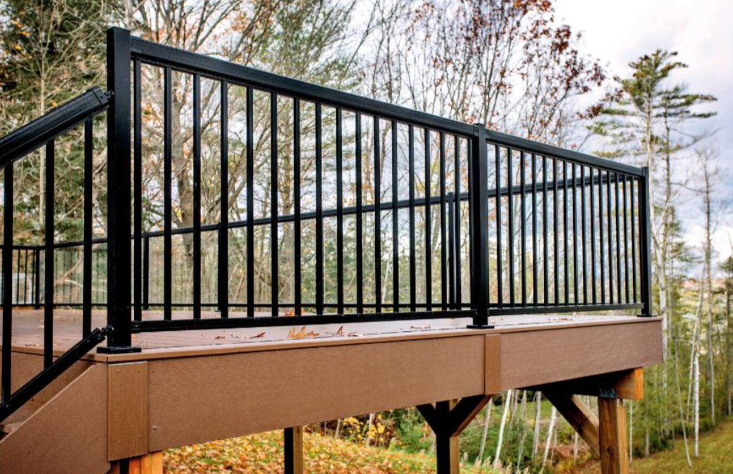 Raised composite deck with black aluminum railing in a wooded backyard