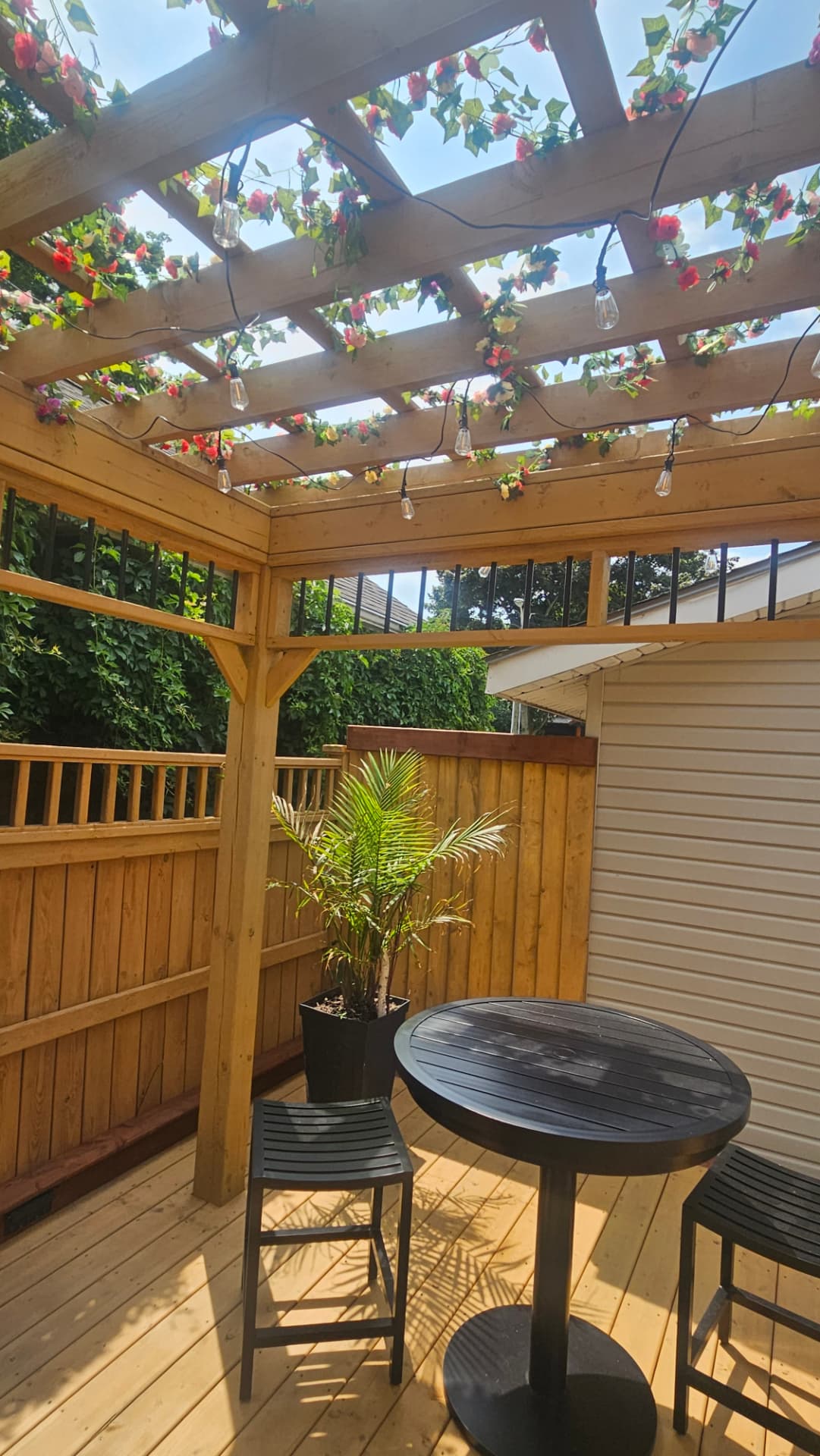 Cedar pergola ceiling with string lights and flowering vines over a new cedar deck