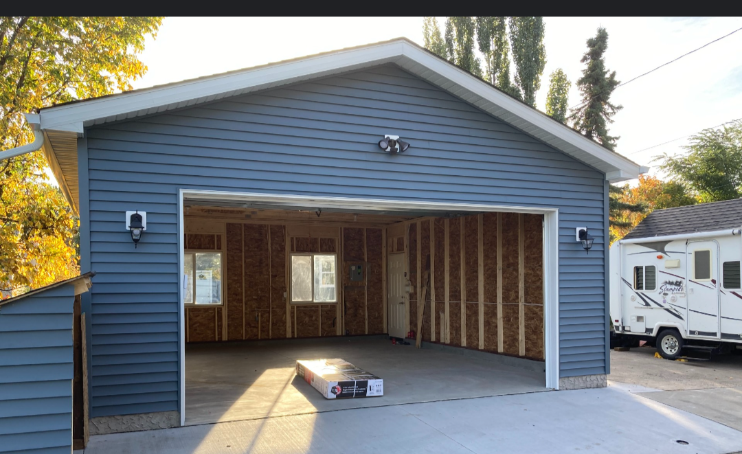 New detached garage with blue siding, white trim and a wide door opening