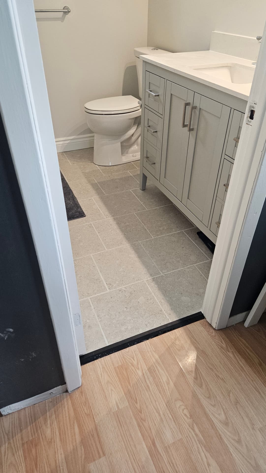 Finished bathroom renovation with a grey vanity, tiled floor and toilet