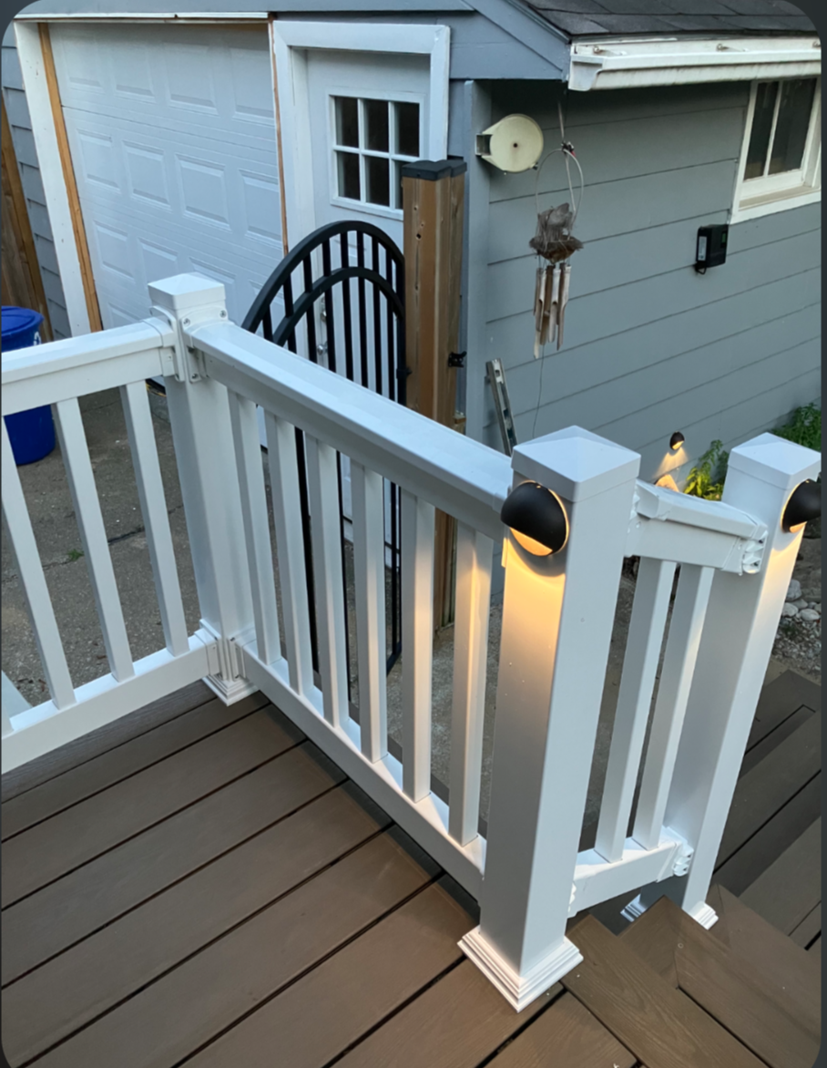 Composite deck with white vinyl railing, integrated gate and post cap lighting