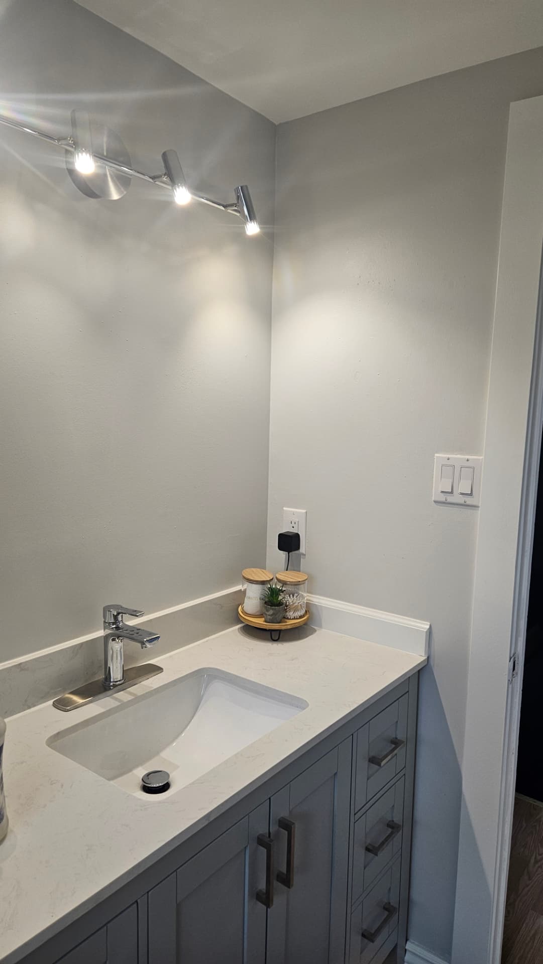 Renovated bathroom with a grey vanity, quartz counter and modern lighting